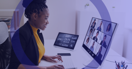 A woman sat down, looking at a screen as she is in a virtual meeting